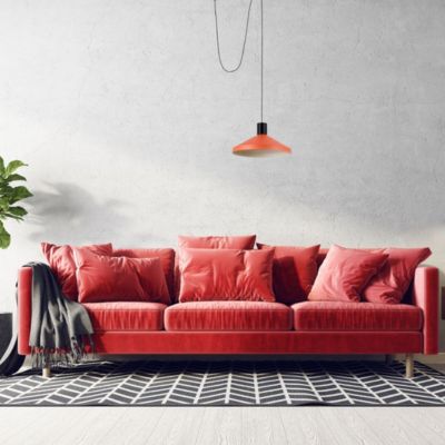 Suspension orange Kombo de la marque Faro dans un salon avec un canapé rouge